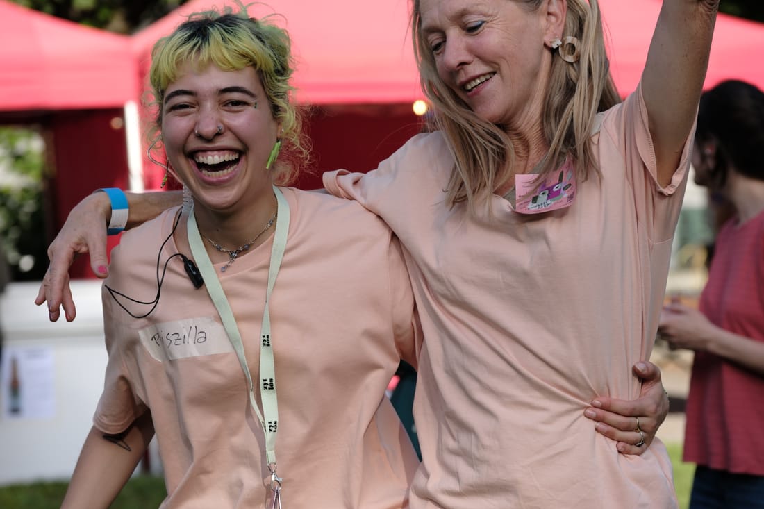 Zwei Helfende im Openair-Shirt mit Namensschild lachen gemeinsam